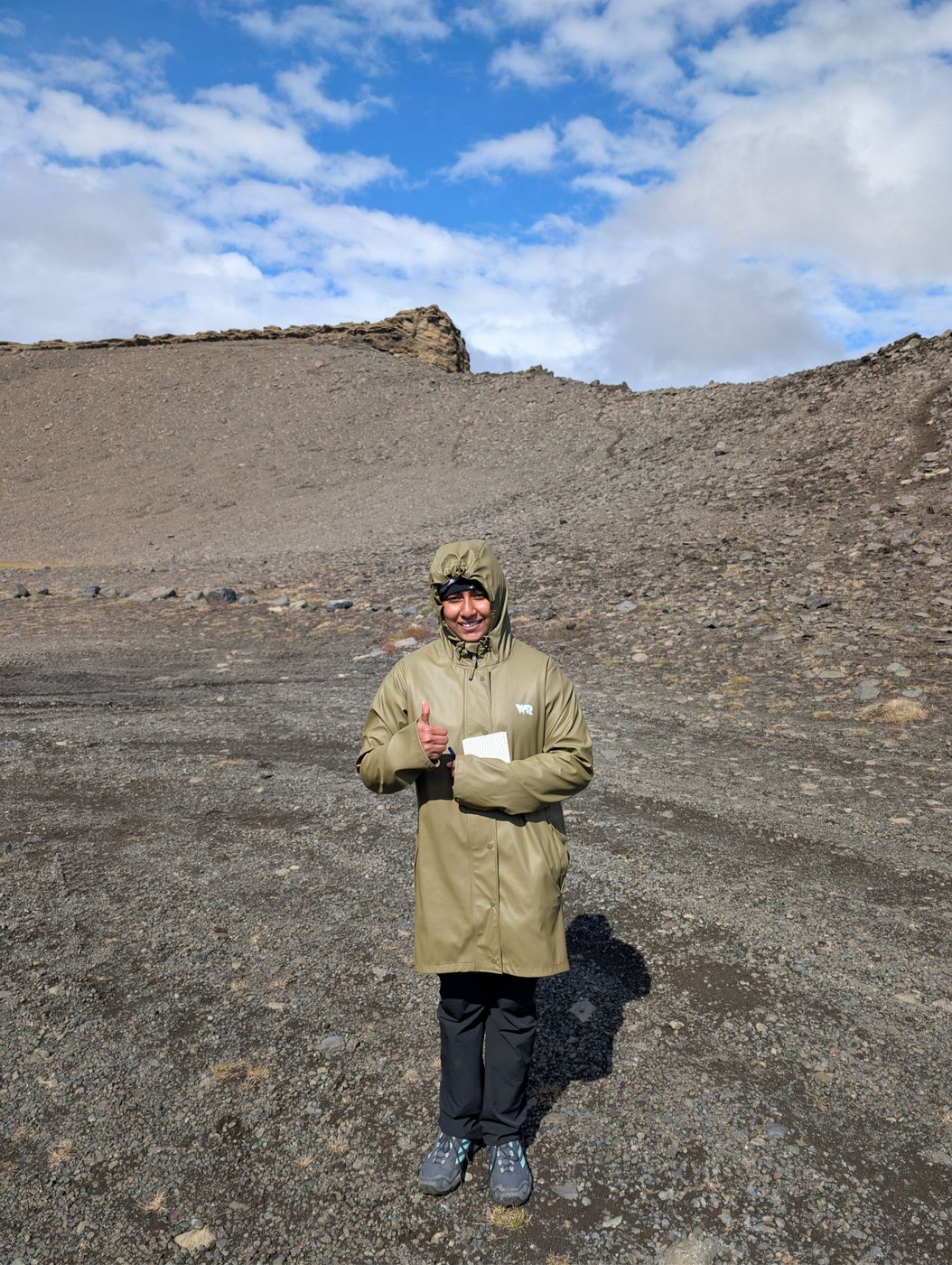 Gouri in a green rain jacket in volcanic terrain in Iceland